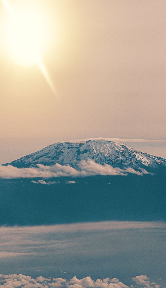 Stunning aerial view of Mount Kilimanjaro at sunrise, showcasing its snow-capped peak and surrounding clouds.